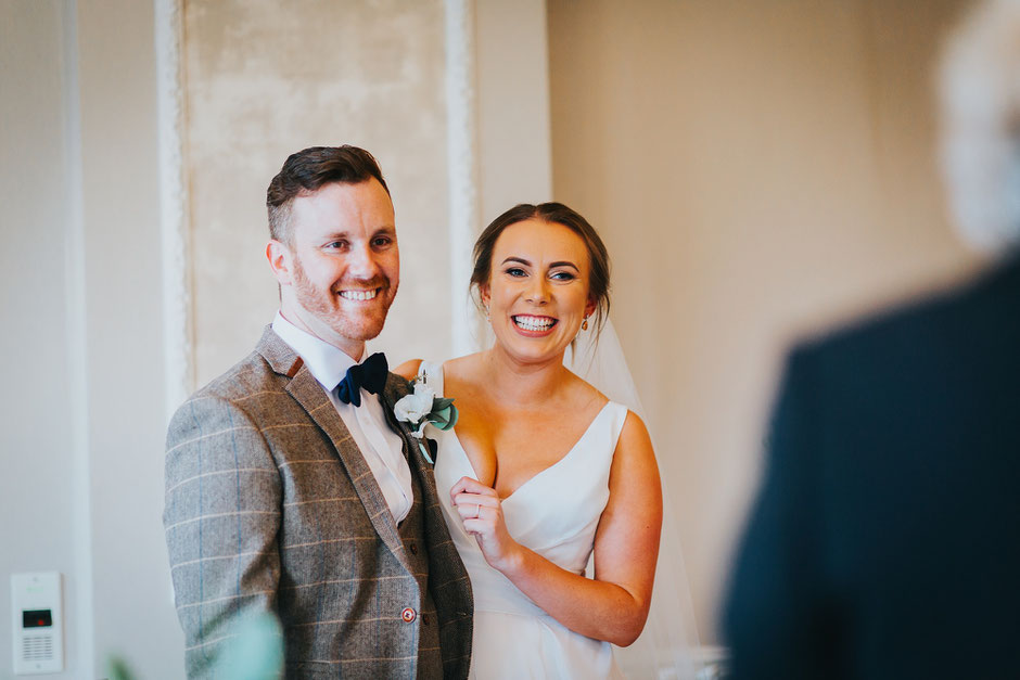 bride and groom looking really happy as the registrar at their wedding tells them they are now man and wife