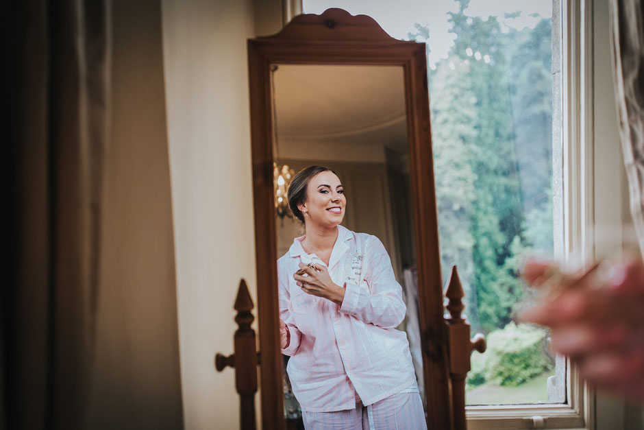 reflection of a bride in the mirror putting perfume on