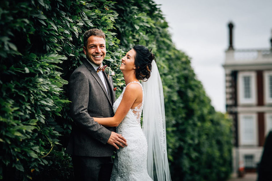 portrait of a bride and groom resting on a bush in the gardens of knowsley hall
