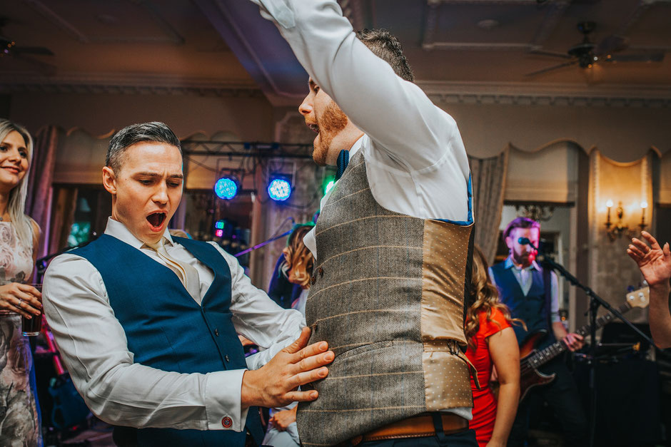 two men dancing at a wedding dressed in waistcoats