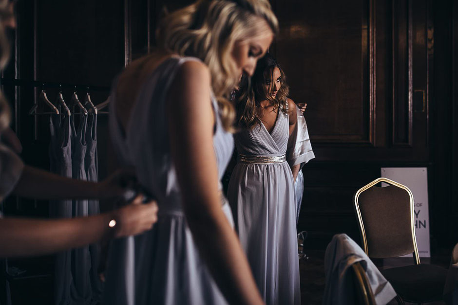 two bridesmaids putting their dresses on