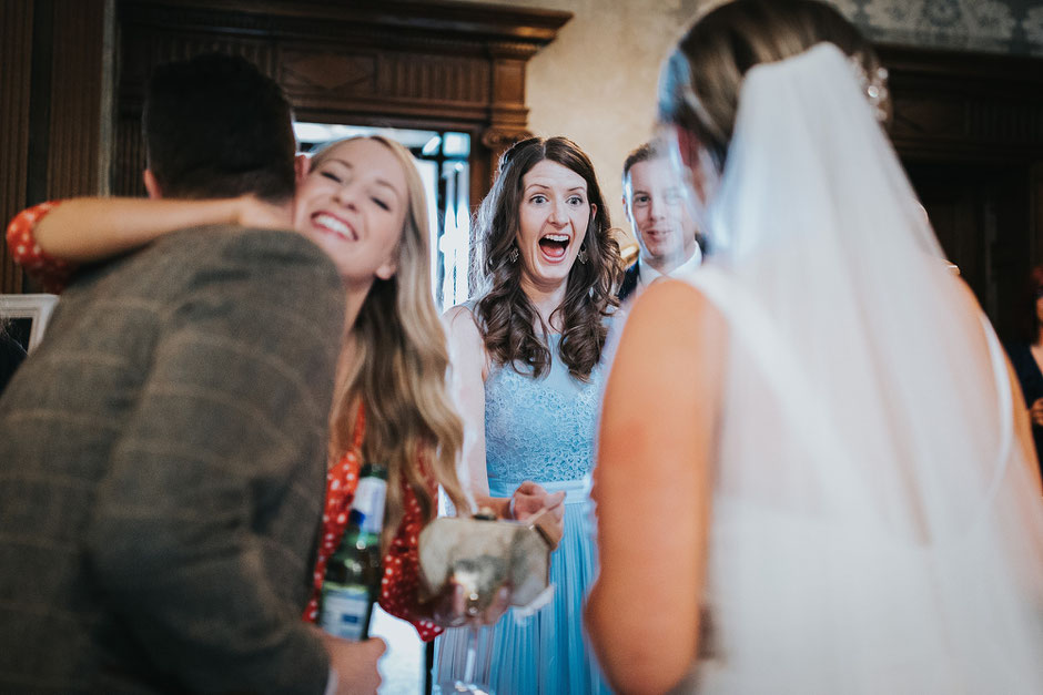 candid photo of a wedding guest dressed in a blue dress excited to see the bride