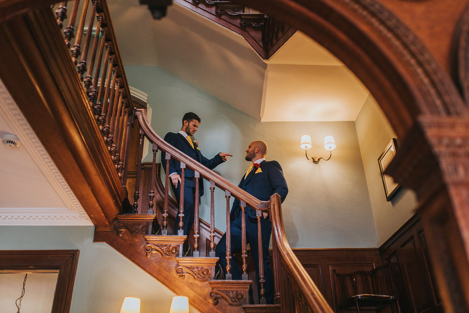 Two men having a joke on the stairs at Soughton Hall