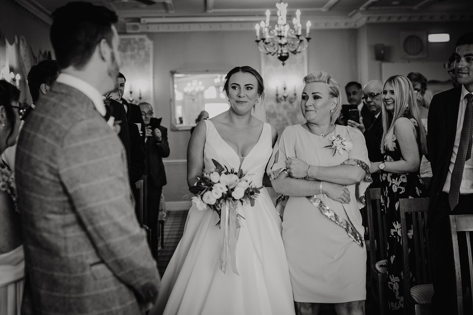 black and white photograph of a bride walking towards her soon to be husband with tears in her eyes