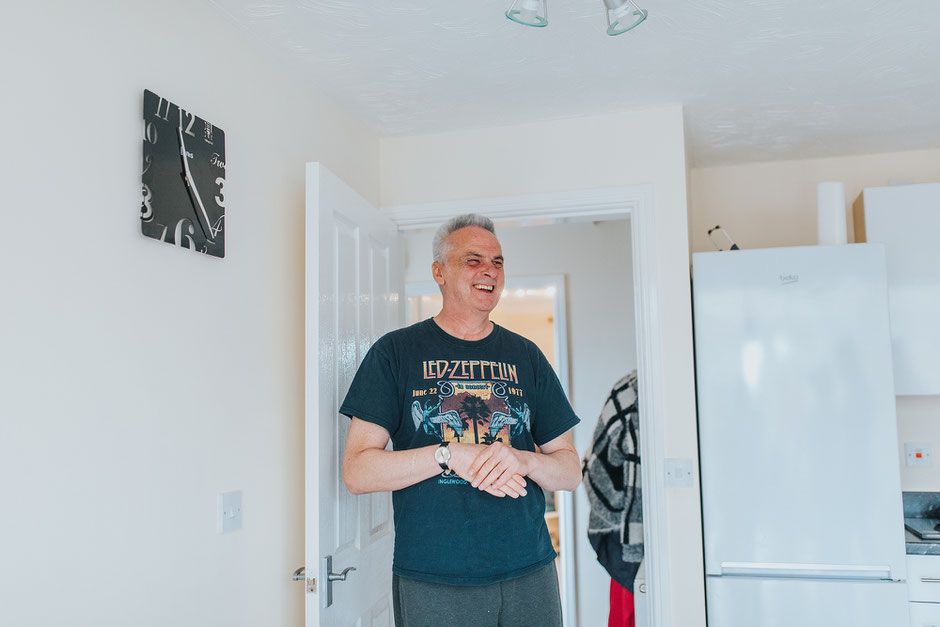 Man laughing whilst stood in the kitchen wearing a led zeppelin t shirt