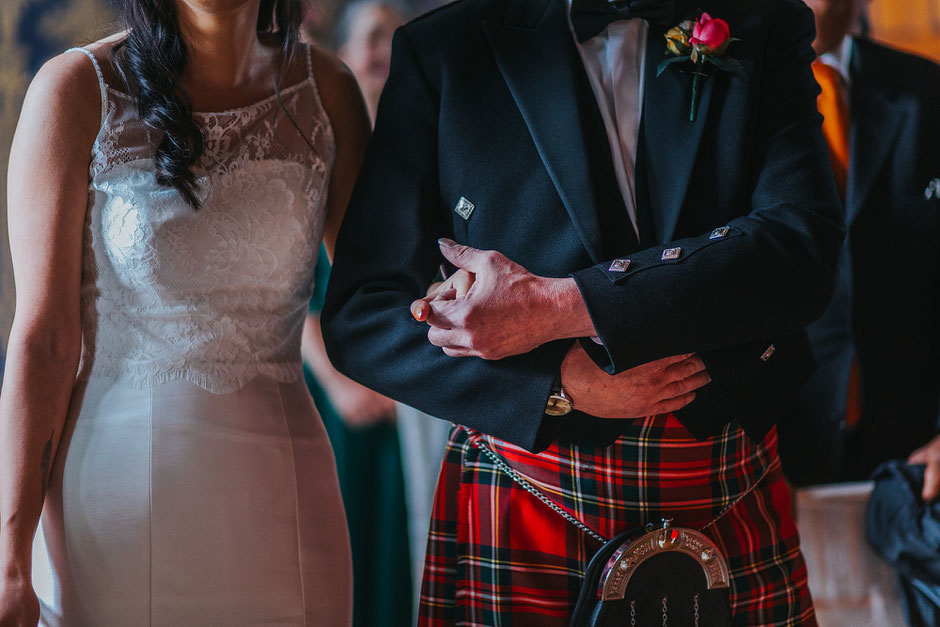 Close up photograph of a brides father holding her hand as she walks down the aisle at Soughton Hall