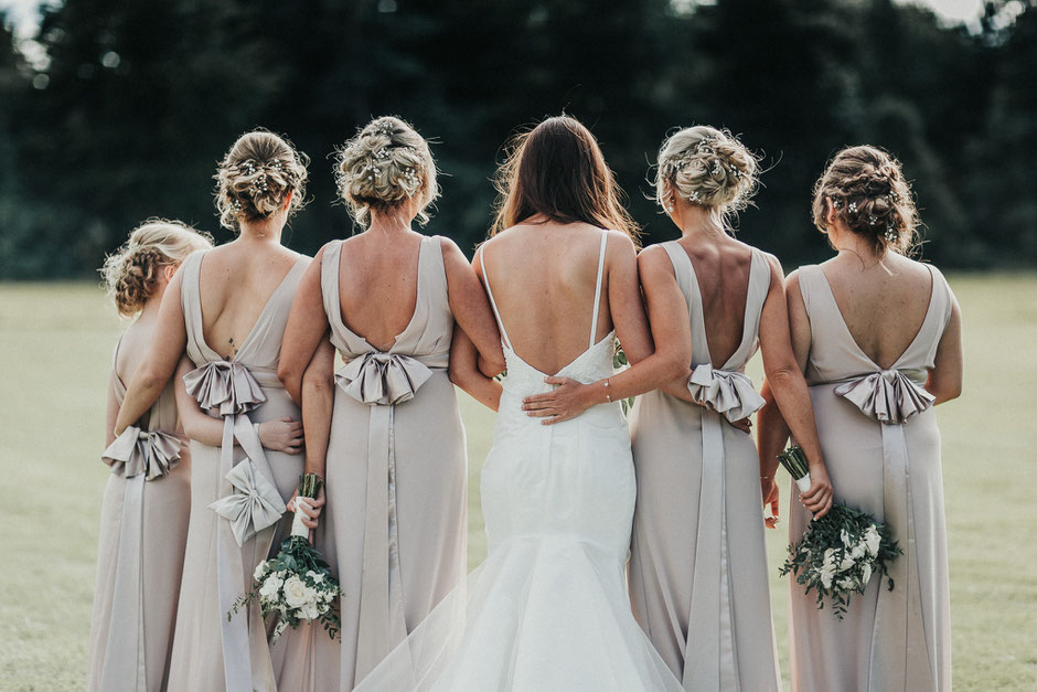 a photograph of a bride and her bridesmaids showing the details on the backs of their dresses