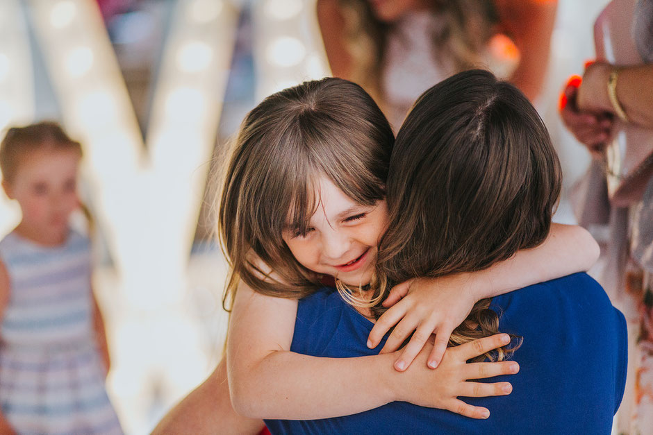 little girl giving her mum a hug with a big smile on her face