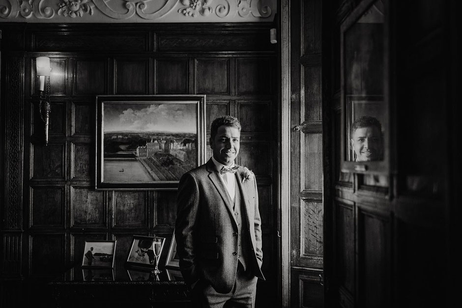 black and white portrait of a groom in a tweed suit lit with window light
