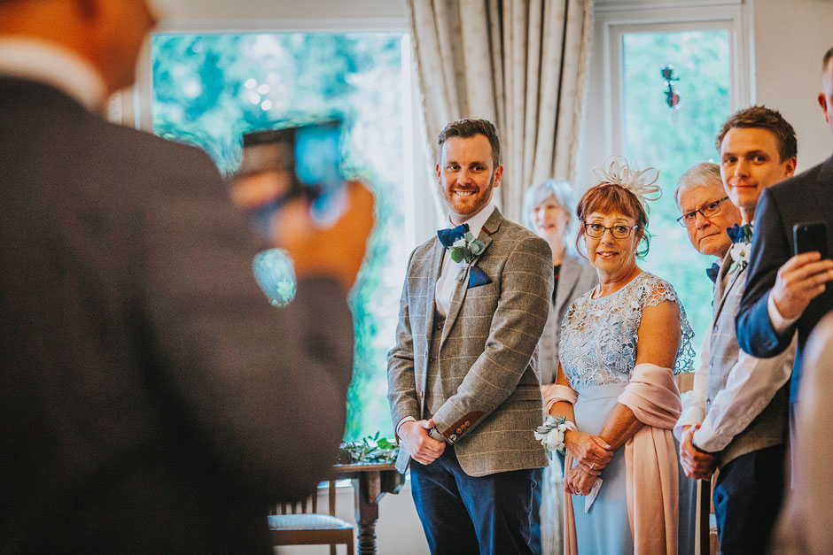 Groom and his mother turned to look up the aisle as his soon to be bride walks to meet him