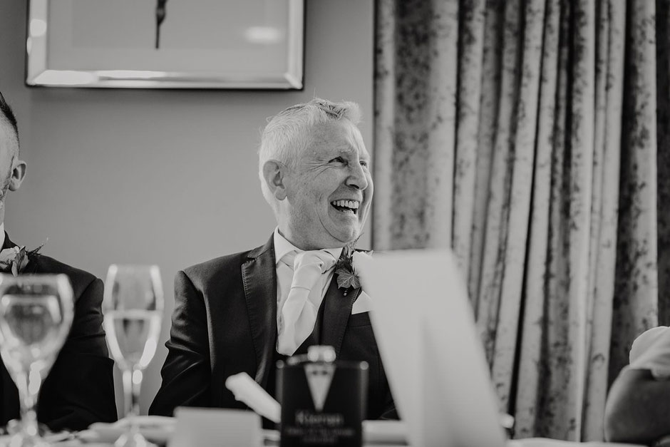 black and white photograph of a man laughing during wedding speeches