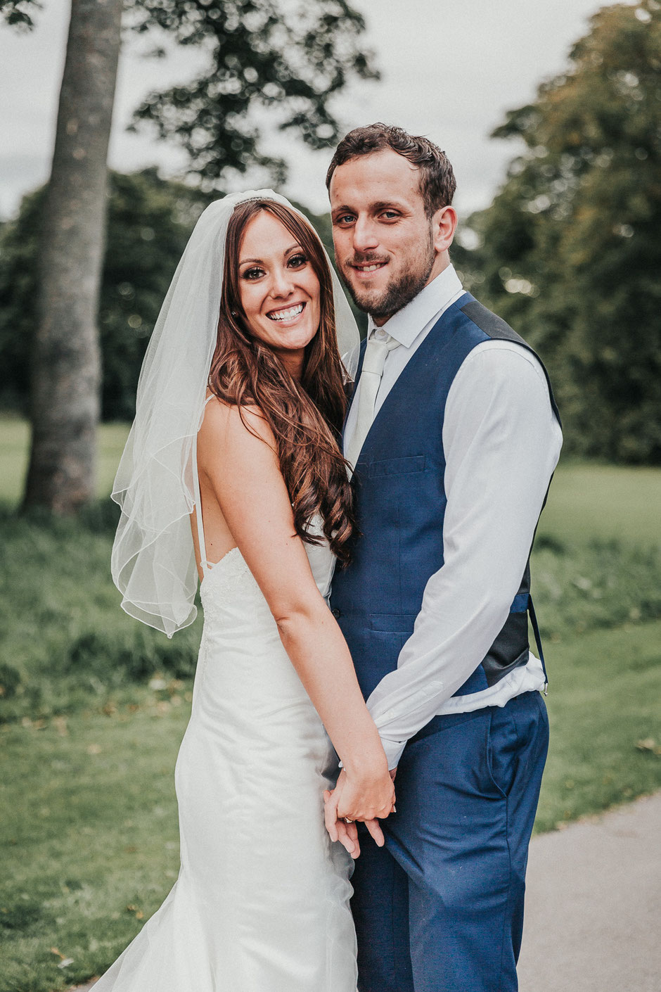 a bride and groom holding hands and smiling at the camera