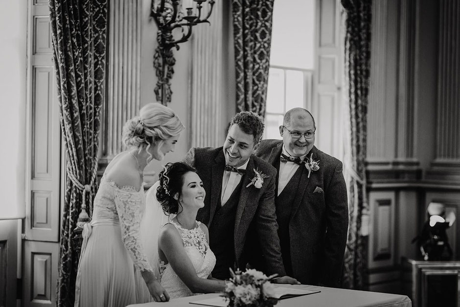 natural black and white photograph of a bride and groom signing the register