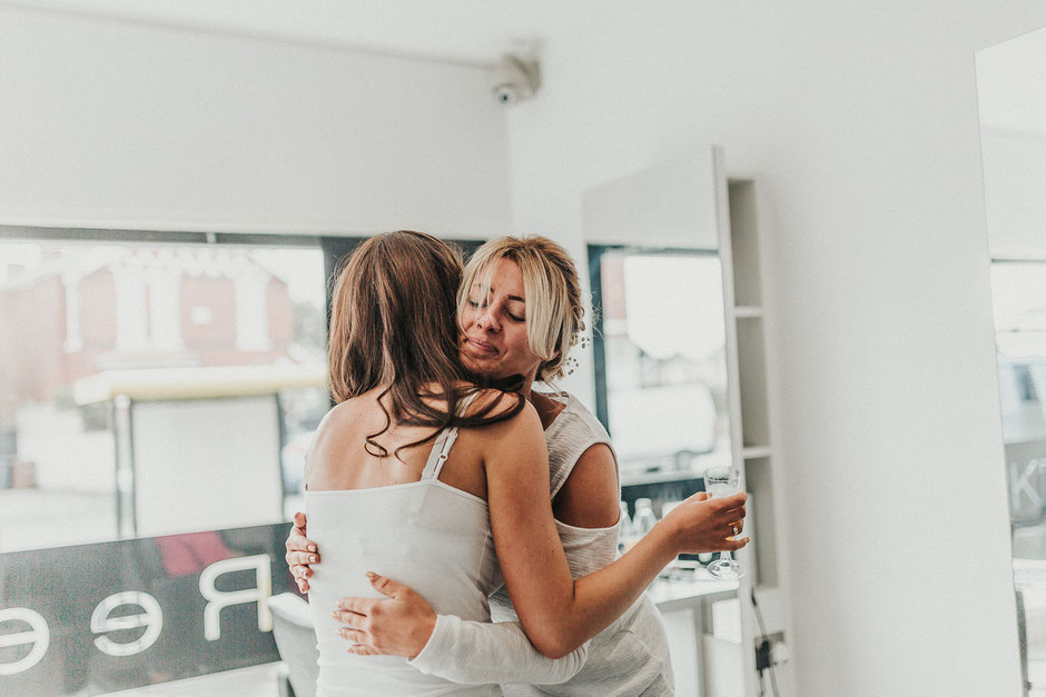 bride and bridesmaid hugging in a hair salon