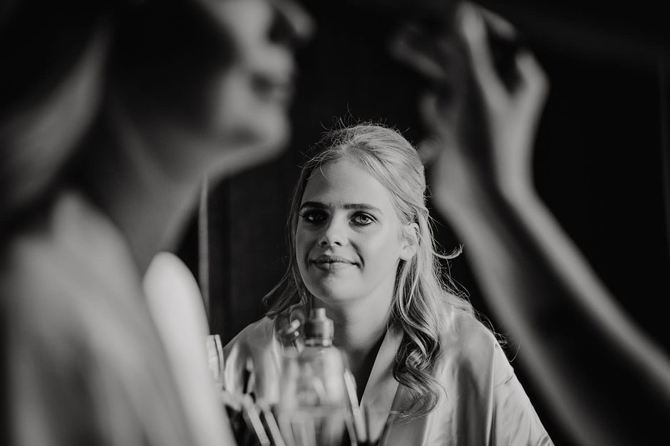 a photograph of a girl watching another girl getting her make up done at a wedding