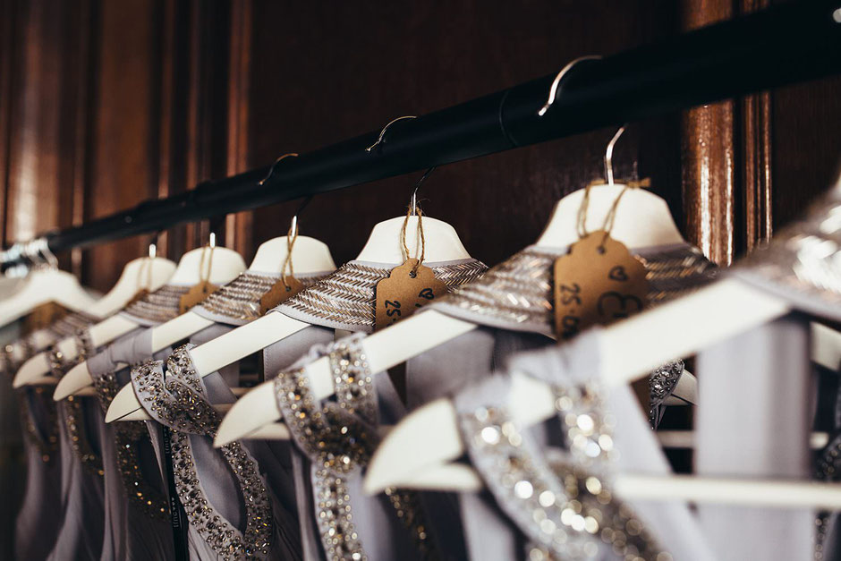Close up photograph of grey embellished bridesmaids dressed on white hangers with brown name tags