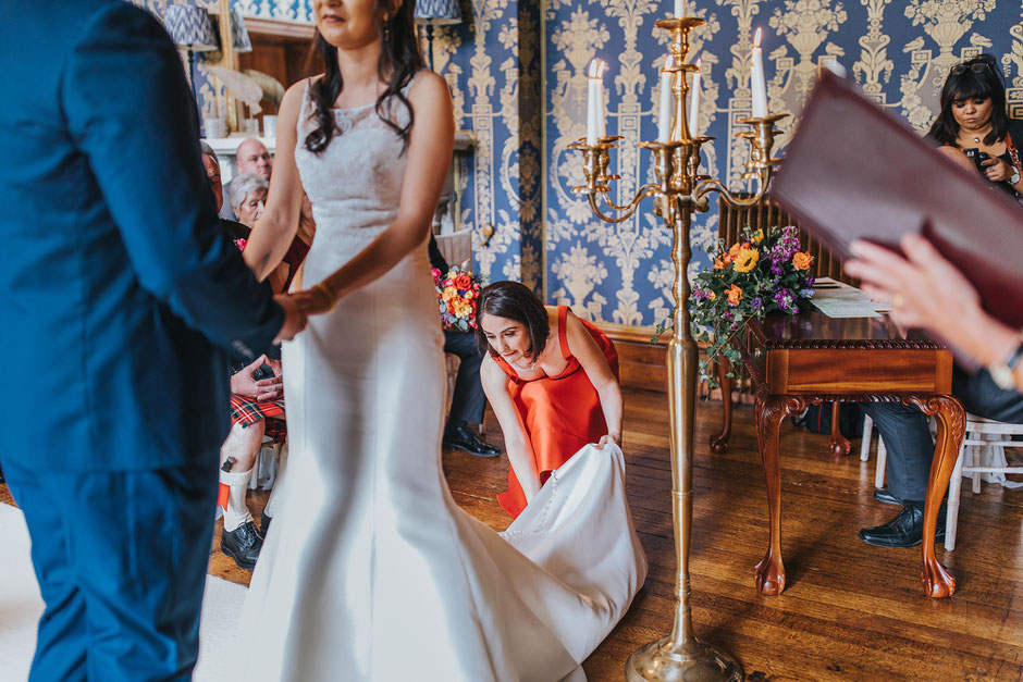 Bridesmaid sorting the brides dress as she gets married