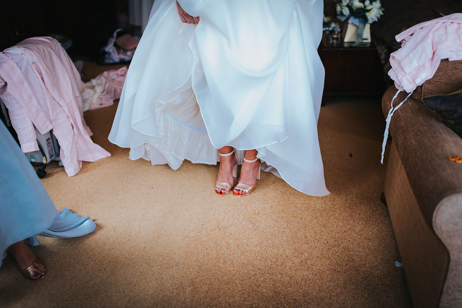a bride holding up her dress so you can see her gold shoes underneath