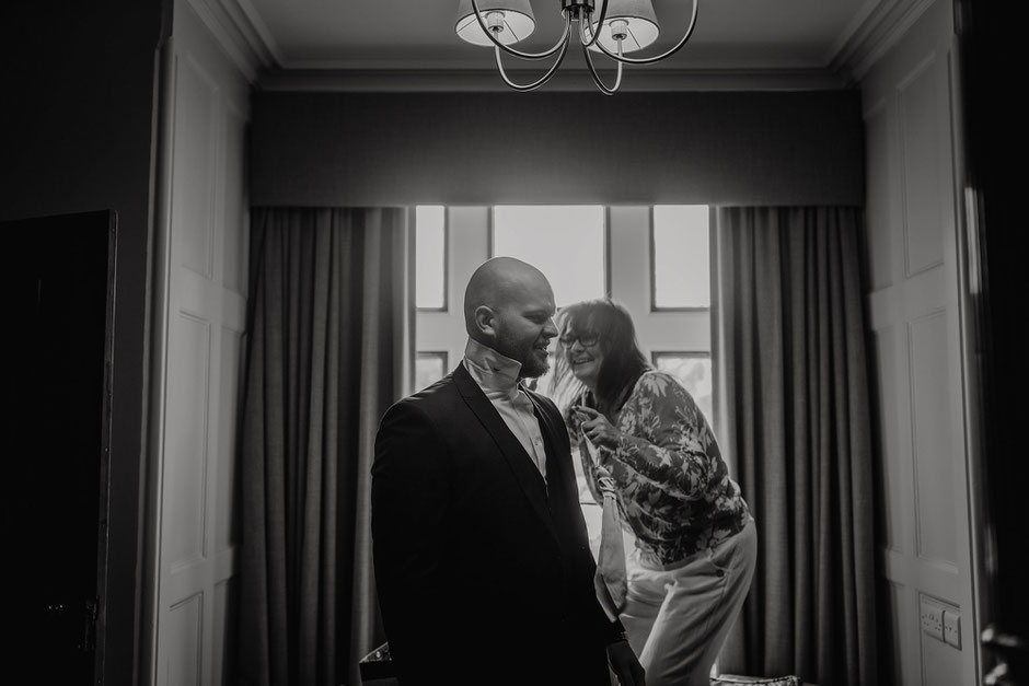 A groom at Soughton Hall being dressed by his Mum on his wedding day