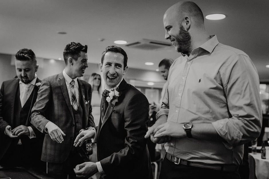 black and white portrait of a groom laughing with friends whilst playing poker