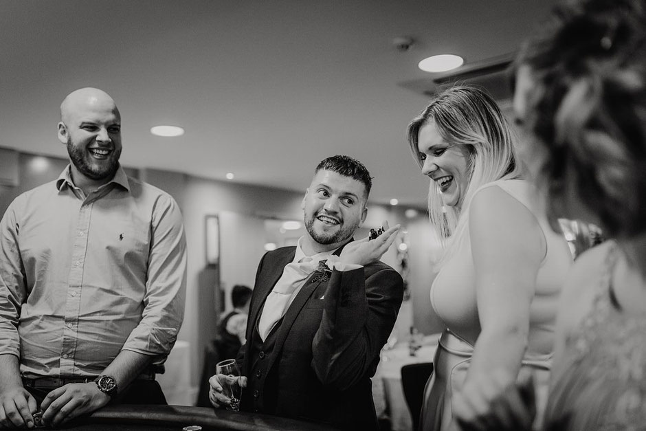 black and white photograph of a wedding guest looking happy with his winnings from poker