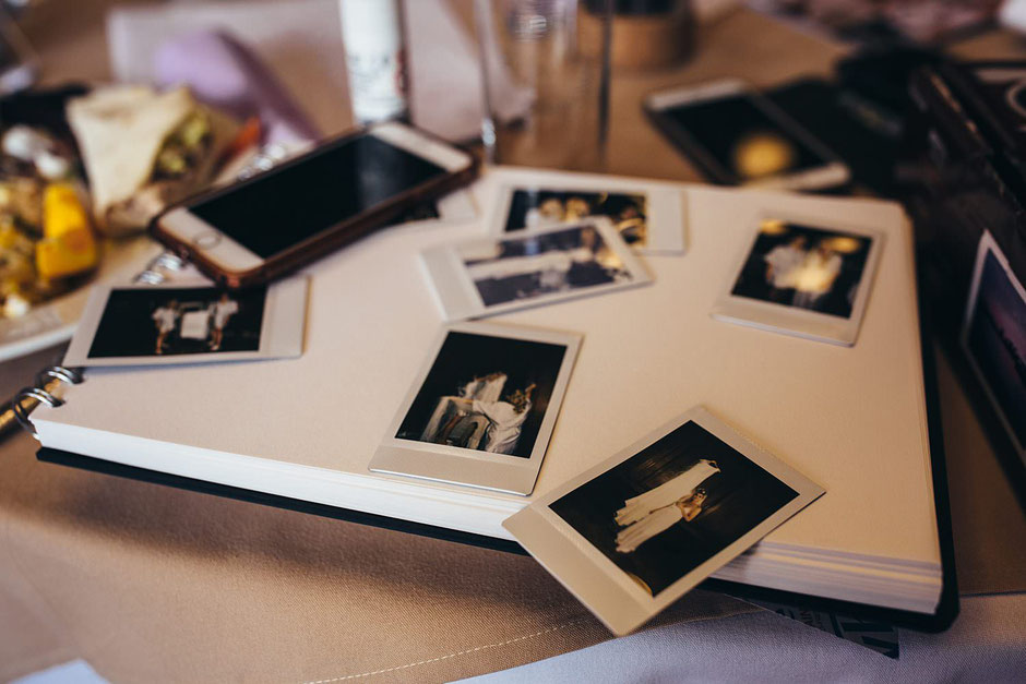 lots of polaroid photographs laying on a book waiting to be stuck in