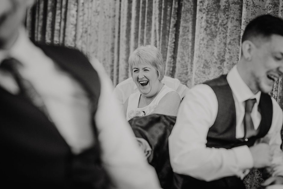candid black and white photograph of a lady laughing during wedding speeches