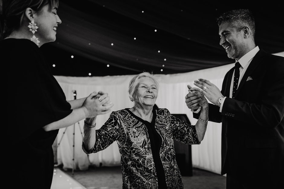 elderly lady on the dancefloor smiling whilst dancing with family members
