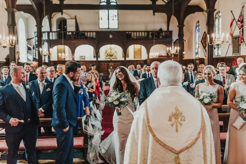 a candid photograph of a bride reaching her groom in church