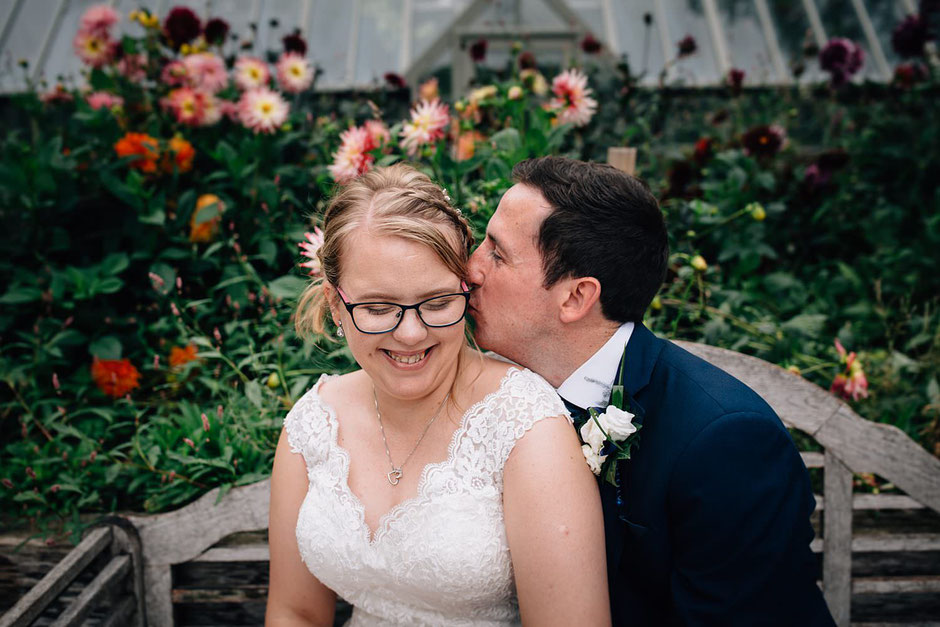 colour photograph of a bride and groom sat on a bench