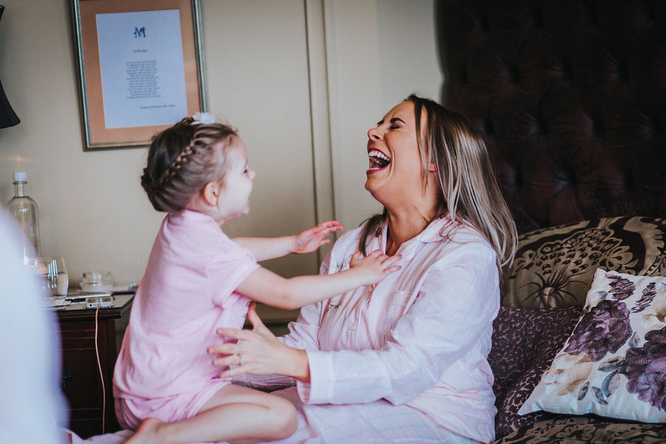 a lady and child playing on a bed in a hotel room