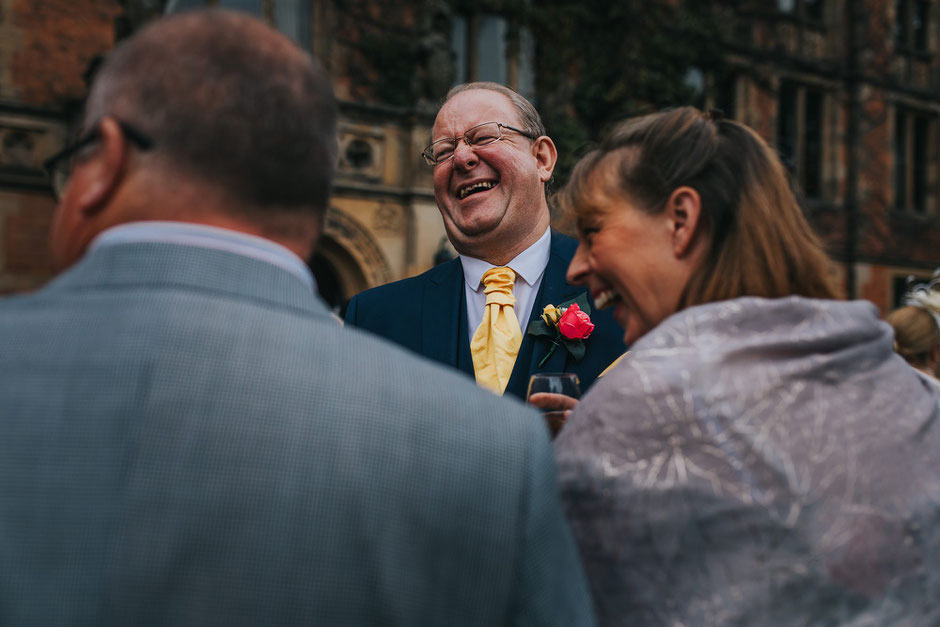 father of the groom laughing amongst a group of people