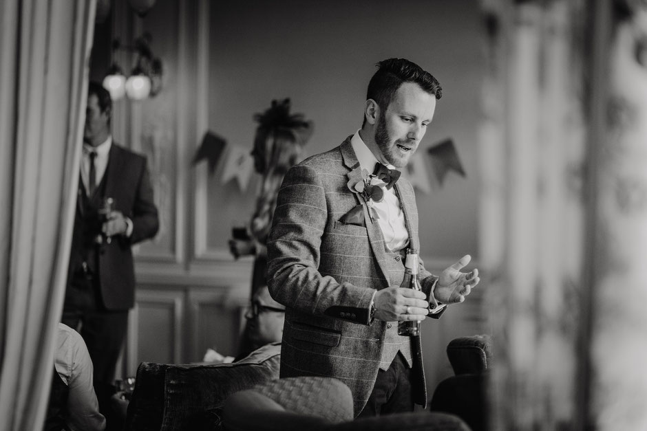 candid black and white photograph of a groom chatting to guests at his wedding reception