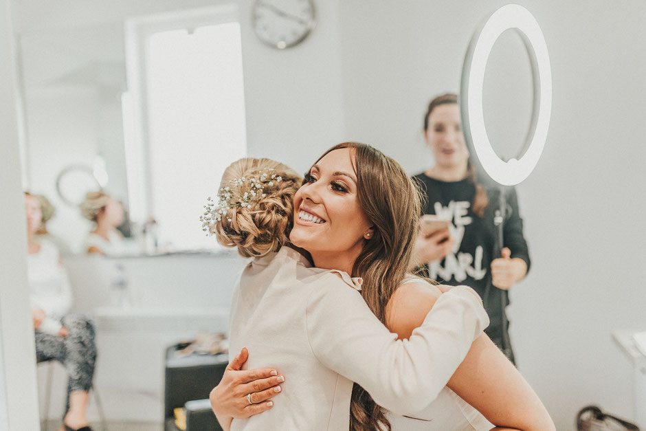 bride having a cuddle with her flower girl in a hair salon