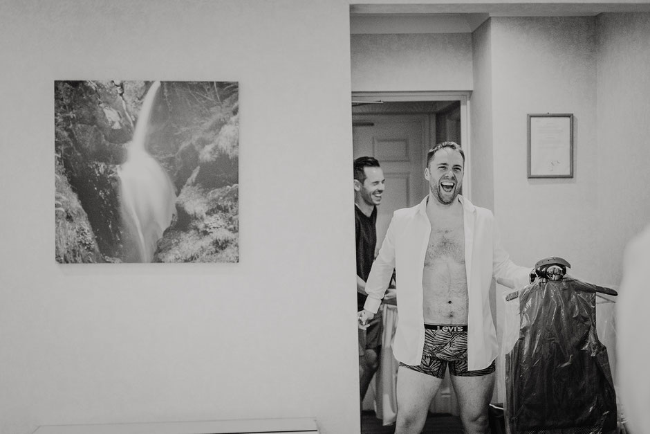 Two men walking into a hotel room and laughing
