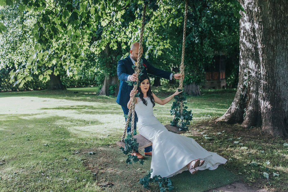 groom pushing his bride on the swing at soughton hall