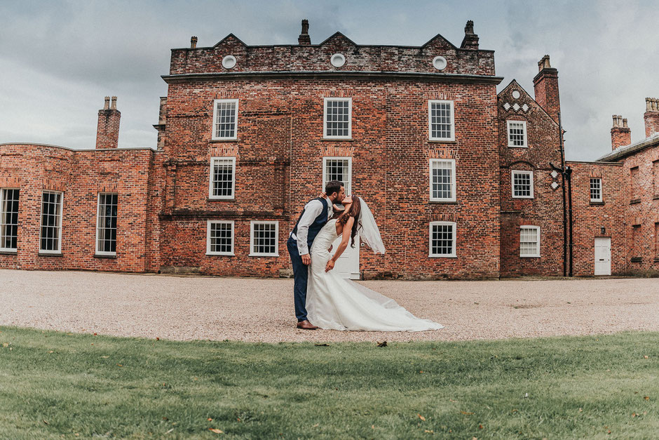 bride and groom kissing in front of meols hall