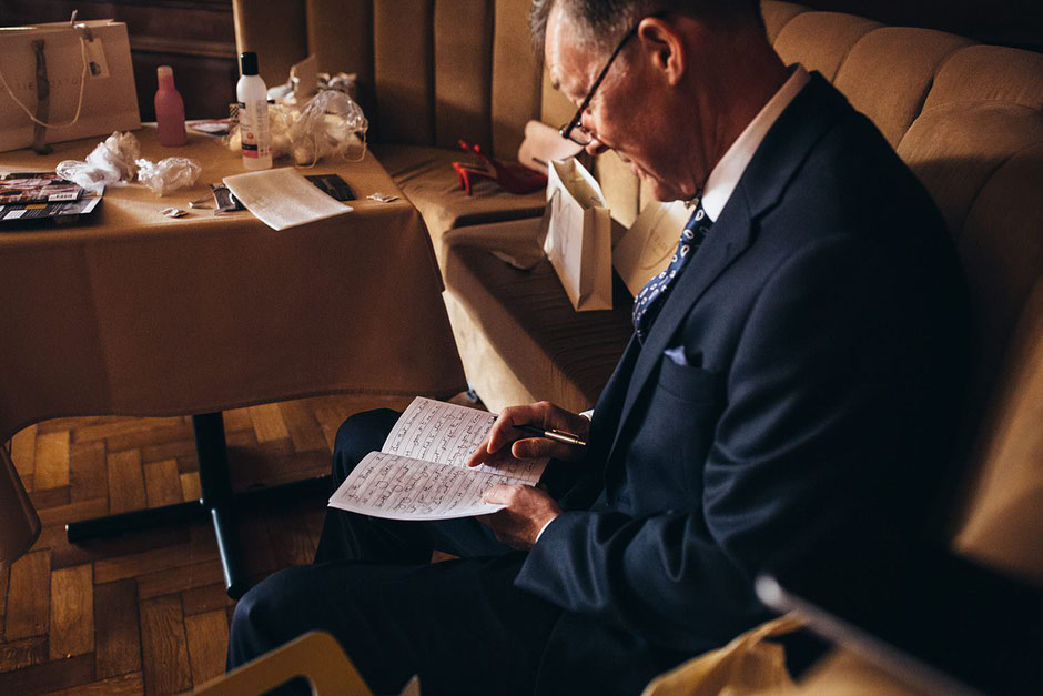a man sat down looking in a notebook where he is making final notes for his father of the bride speech