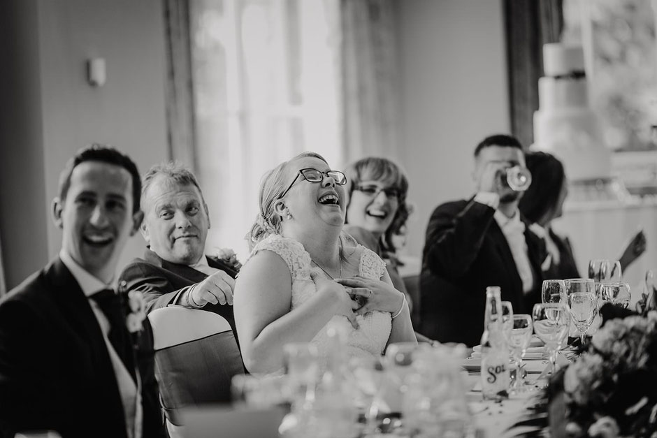 black and white photograph of a bride laughing during speeches