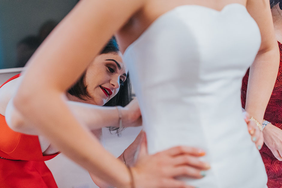 Bride having her dress done up