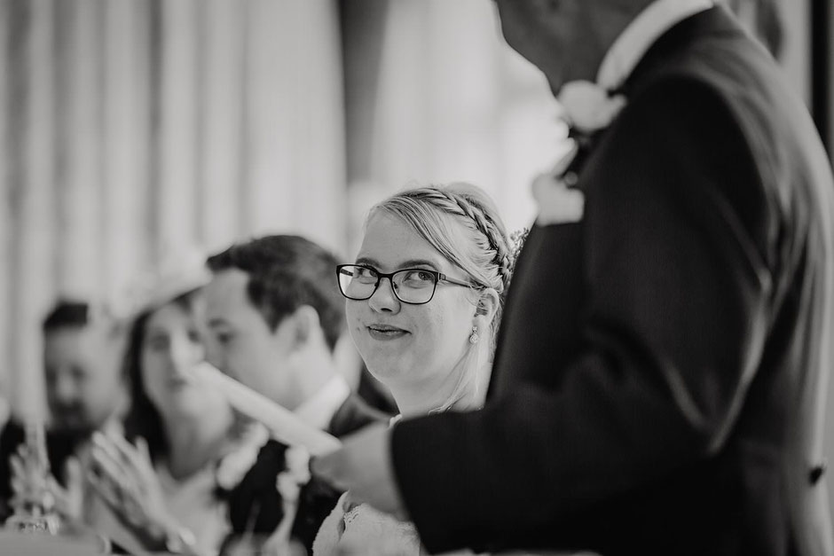 black and white photograph of a bride looking up at her dad during his speech