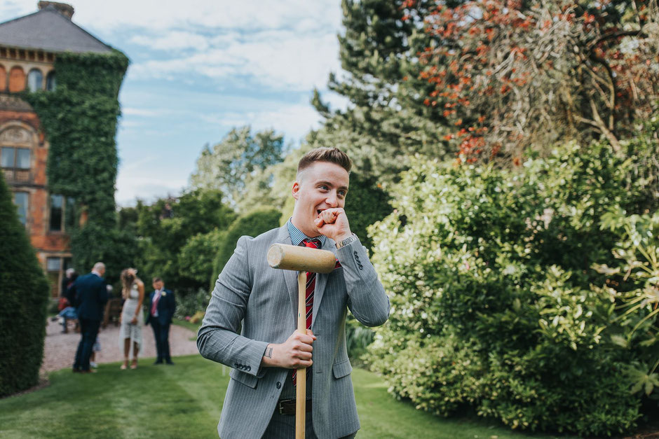 a man at soughton hall playing lawn games dressed in a grey suit with red tie