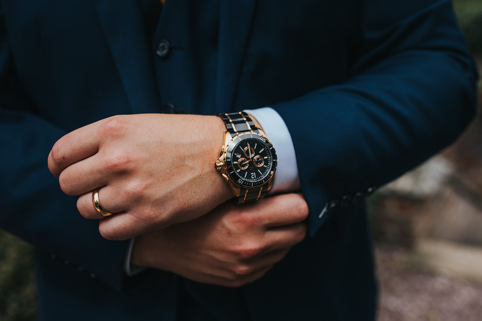 Close up detail shot of a grooms watch and and wedding ring