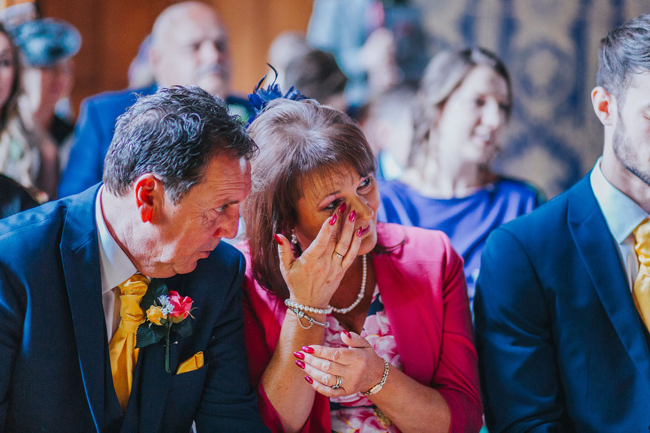 A photograph of the mother of the groom crying during the wedding ceremony