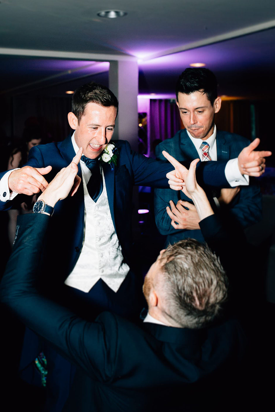 a groom and his friend laughing with each other on the dancefloor
