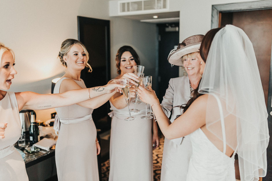 a bride, her mum and bridesmaids all toasting