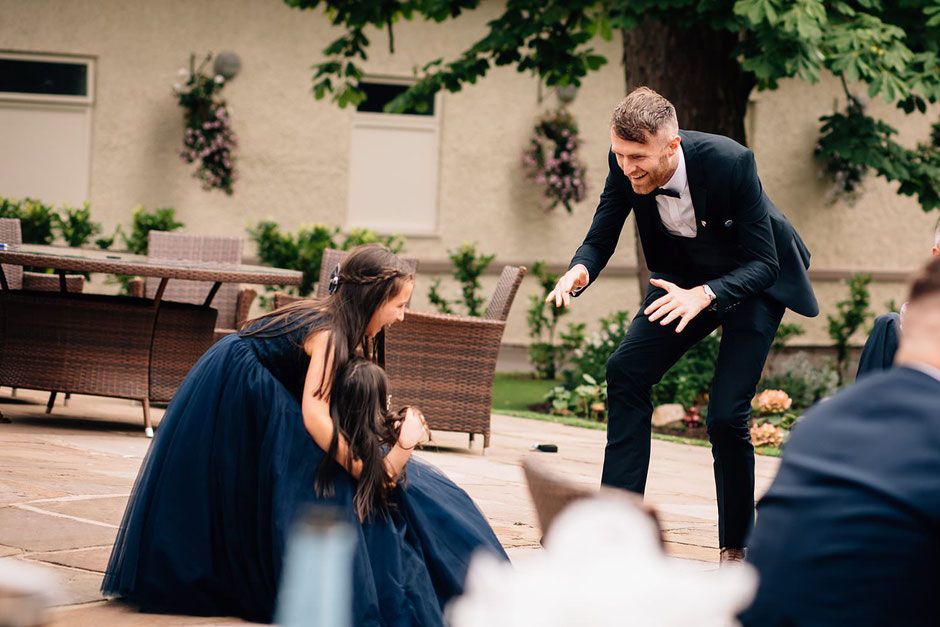 a photograph of a man chasing two bridesmaids at a wedding