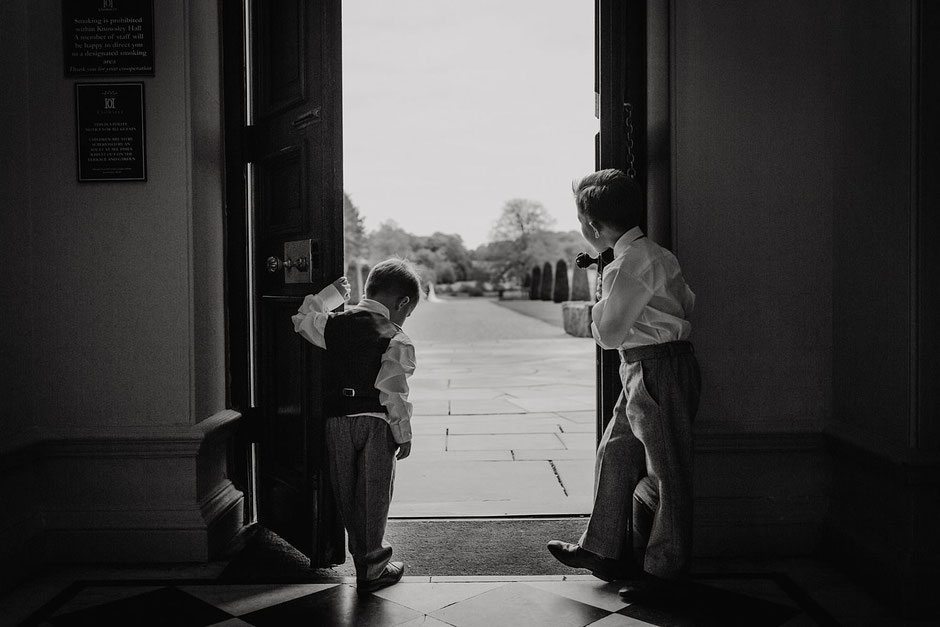 black and white photograph of two boys holding open a large set of doors