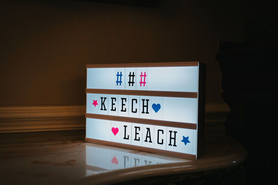 a light up sign with the wedding hashtag displayed in colourful lettering