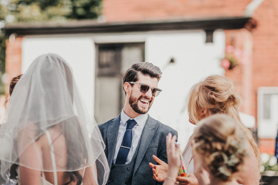 a man in sunglasses and tweed suit laughing